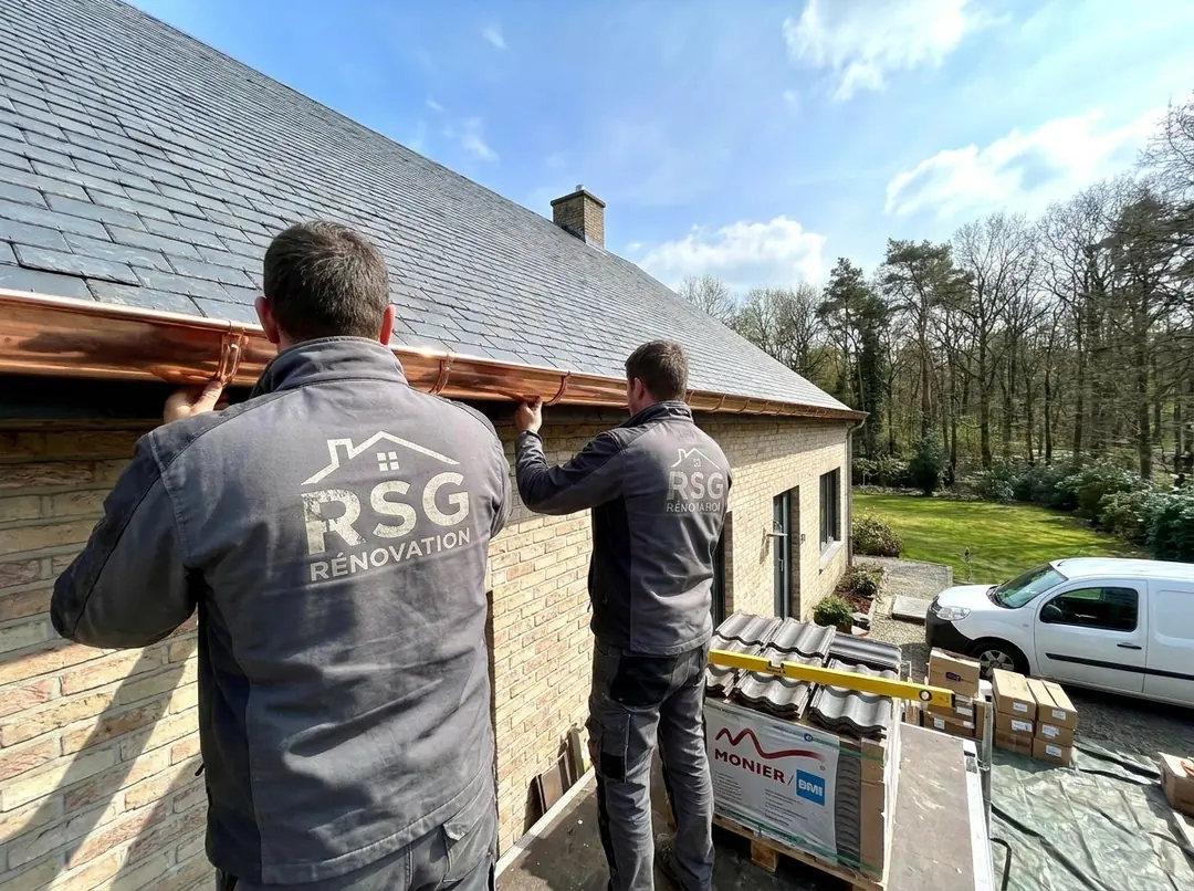 Couvreurs RSG Rénovation posant une gouttière en cuivre sur une villa en briques claires