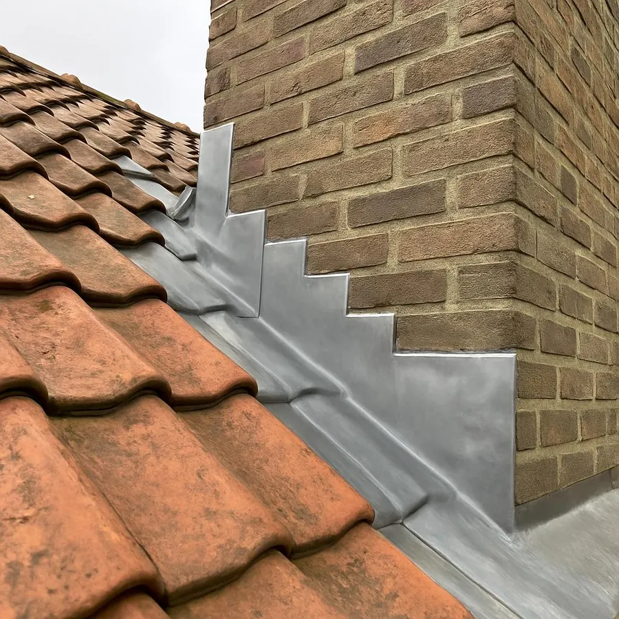 Solin en zinc en escalier au pied d'une cheminée en briques